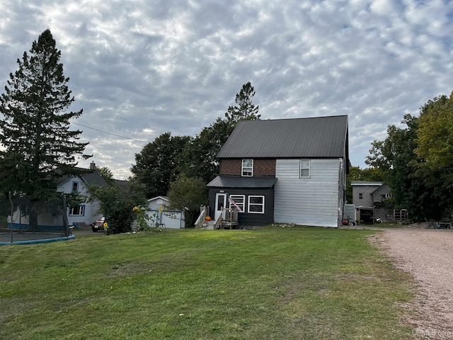 back of house featuring a trampoline and a yard