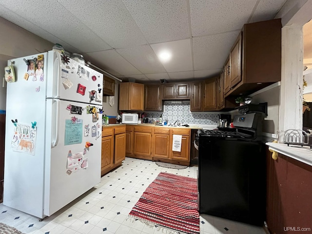 kitchen with decorative backsplash, a drop ceiling, and white appliances