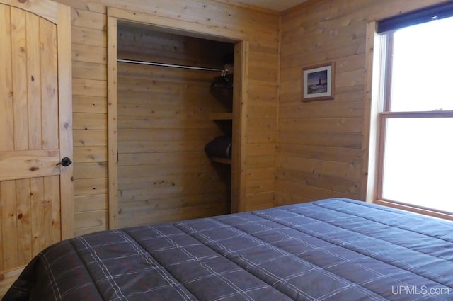 bedroom with a closet and wood walls