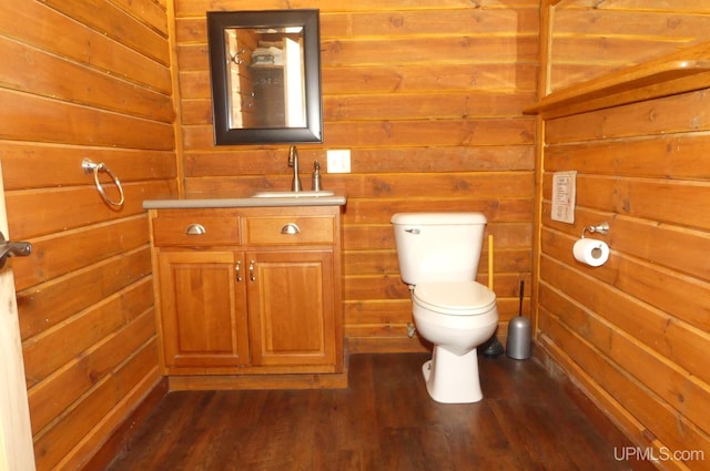 bathroom featuring wood-type flooring, toilet, vanity, and wood walls