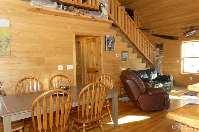 dining room featuring lofted ceiling, wood walls, light hardwood / wood-style floors, and wooden ceiling