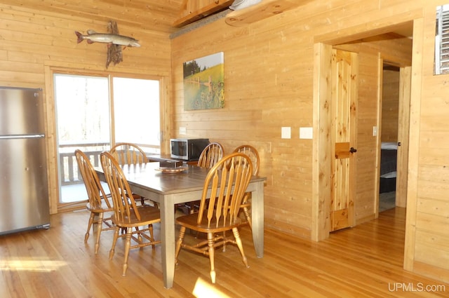 dining room with hardwood / wood-style flooring and wood walls