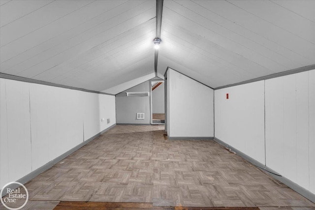 additional living space featuring vaulted ceiling, an AC wall unit, and light parquet flooring