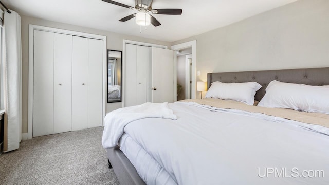 bedroom with carpet floors, ceiling fan, and multiple closets