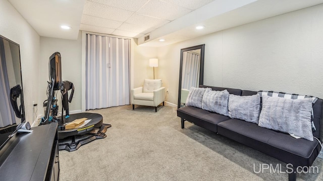 carpeted living room with a drop ceiling