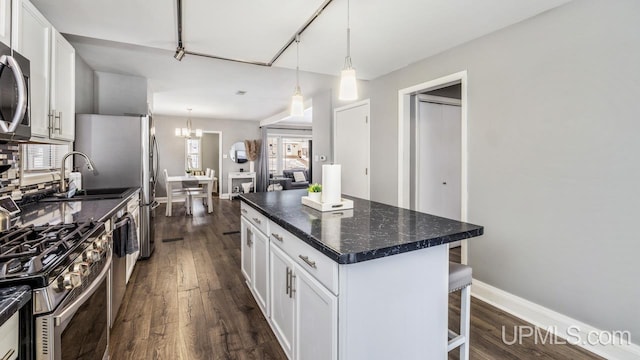 kitchen featuring white cabinetry, a center island, stainless steel appliances, decorative light fixtures, and a breakfast bar