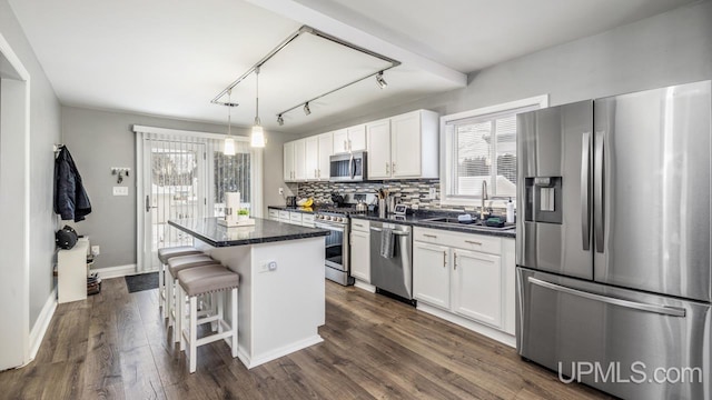 kitchen with sink, a center island, a breakfast bar area, white cabinets, and appliances with stainless steel finishes