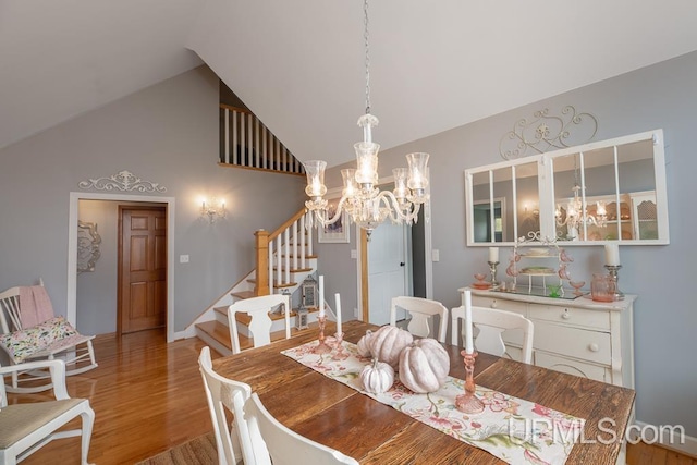 dining room with light hardwood / wood-style flooring, lofted ceiling, and an inviting chandelier