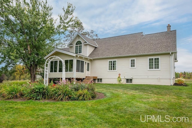 back of property with a lawn and a sunroom