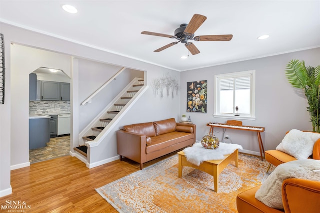 living room with ceiling fan, crown molding, and light hardwood / wood-style flooring