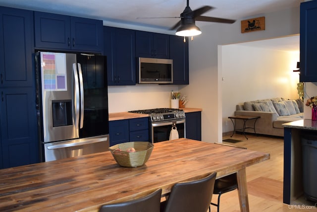 kitchen featuring ceiling fan, butcher block counters, blue cabinets, and appliances with stainless steel finishes