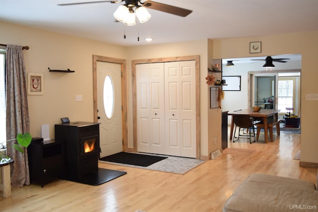 entrance foyer featuring a wood stove, ceiling fan, and light hardwood / wood-style floors