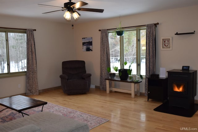 living room featuring ceiling fan, light hardwood / wood-style floors, and a wood stove