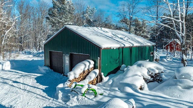 snow covered structure featuring a garage