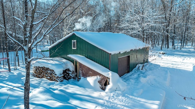 snow covered structure with a garage