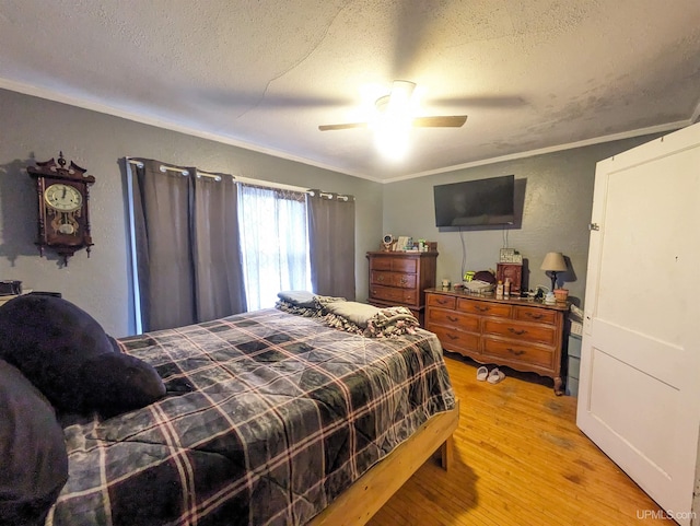 bedroom featuring ceiling fan, ornamental molding, a textured ceiling, and light wood-type flooring