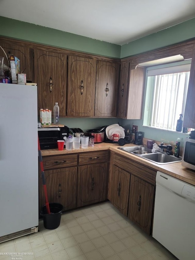 kitchen featuring sink, white appliances, and dark brown cabinets