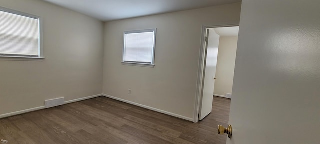 empty room featuring plenty of natural light and dark hardwood / wood-style floors