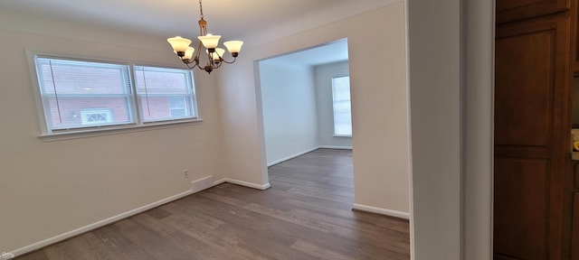 unfurnished dining area featuring wood-type flooring and an inviting chandelier