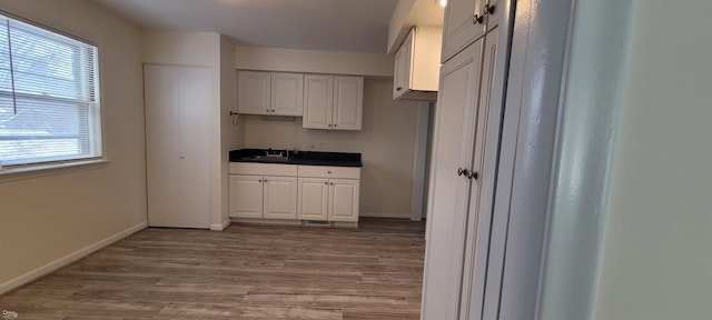 kitchen featuring light wood-type flooring, white cabinetry, and sink