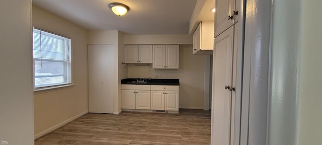 kitchen featuring light wood-type flooring, white cabinetry, and sink