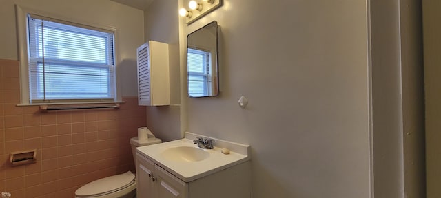 bathroom with vanity, tile walls, and toilet