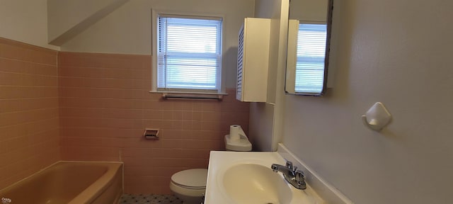 bathroom featuring toilet, tile walls, a tub, and sink