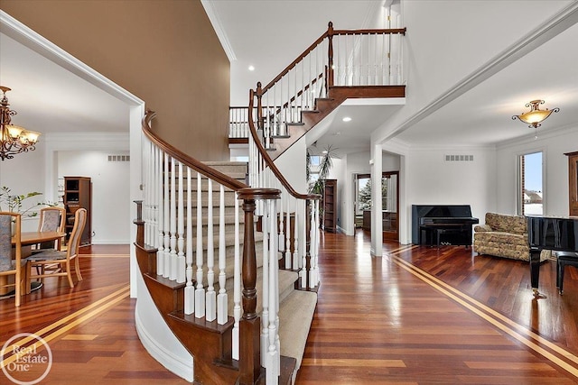 stairway featuring a chandelier, hardwood / wood-style floors, and crown molding