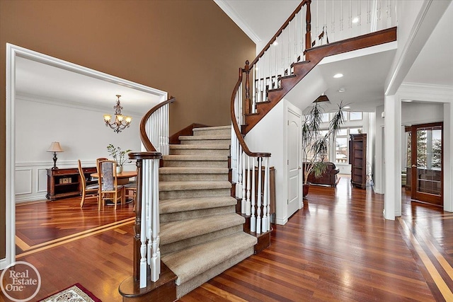 stairs with hardwood / wood-style floors, an inviting chandelier, and ornamental molding