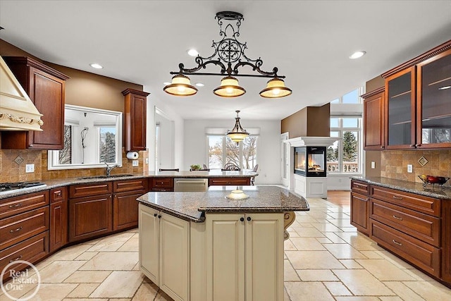 kitchen with tasteful backsplash, stainless steel appliances, sink, a multi sided fireplace, and a kitchen island