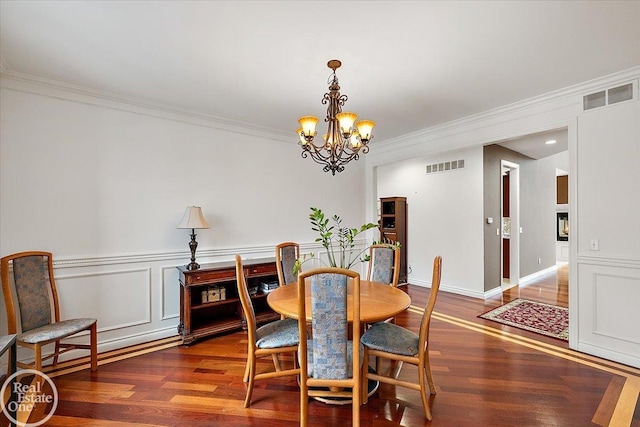 dining room featuring ornamental molding, dark wood-type flooring, and a chandelier