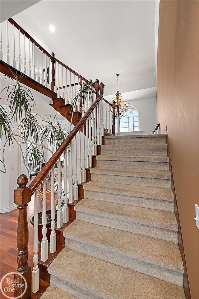 staircase with a notable chandelier and wood-type flooring