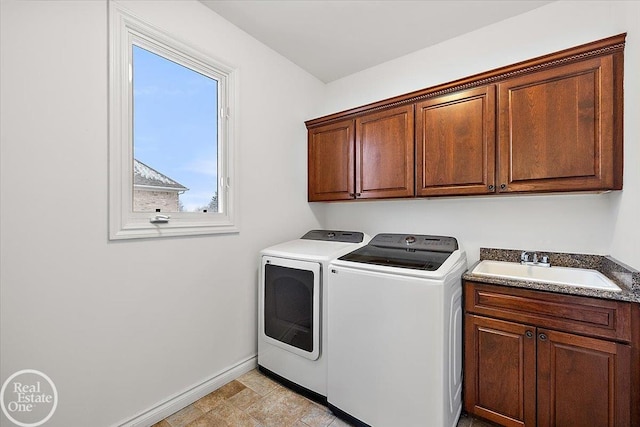 clothes washing area featuring washing machine and clothes dryer, sink, and cabinets