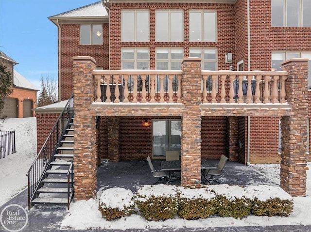 snow covered back of property featuring a balcony