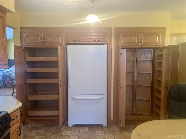 kitchen featuring electric range, pendant lighting, white fridge, and light brown cabinets