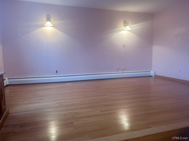 empty room featuring a baseboard heating unit and hardwood / wood-style floors