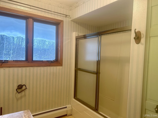 bathroom with a healthy amount of sunlight, baseboard heating, and combined bath / shower with glass door