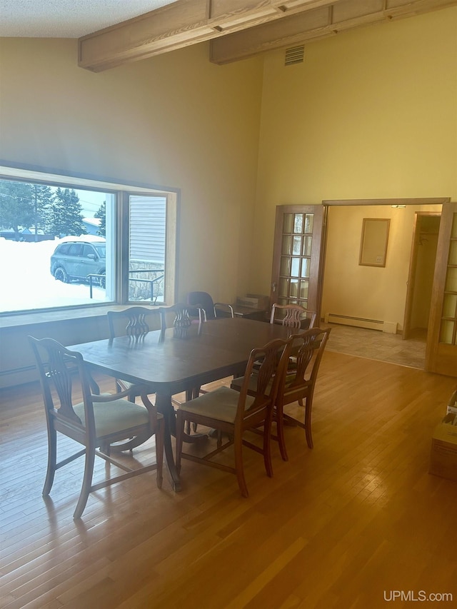 dining space with a textured ceiling, baseboard heating, and light hardwood / wood-style flooring