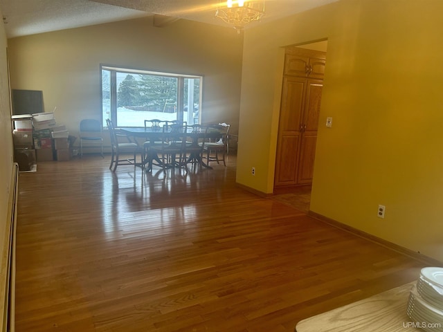 unfurnished dining area featuring vaulted ceiling with beams, a chandelier, and wood-type flooring