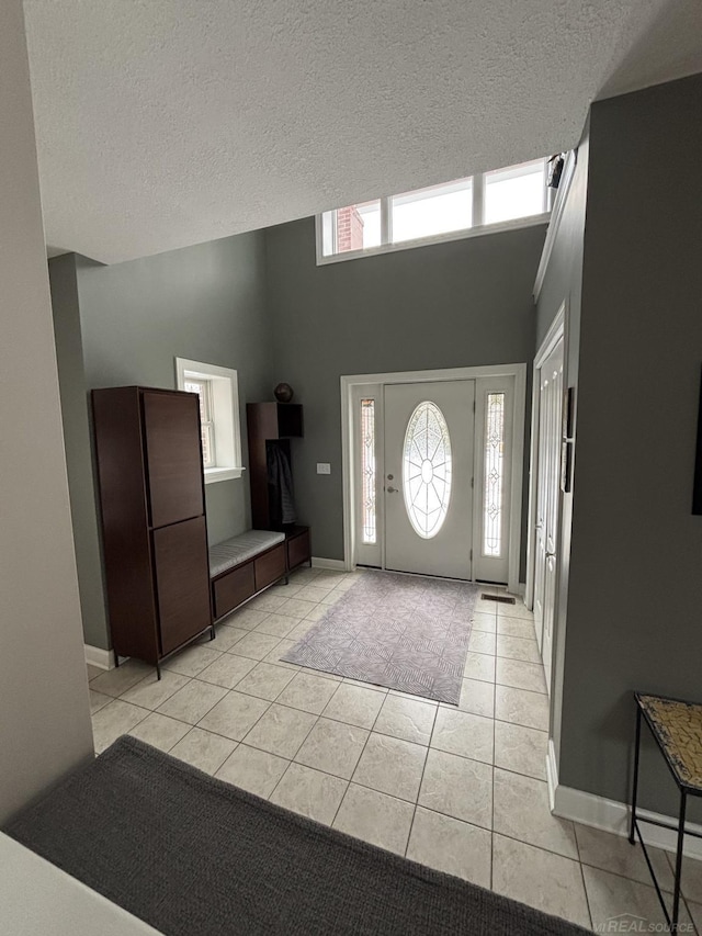 tiled entrance foyer with a high ceiling and a textured ceiling