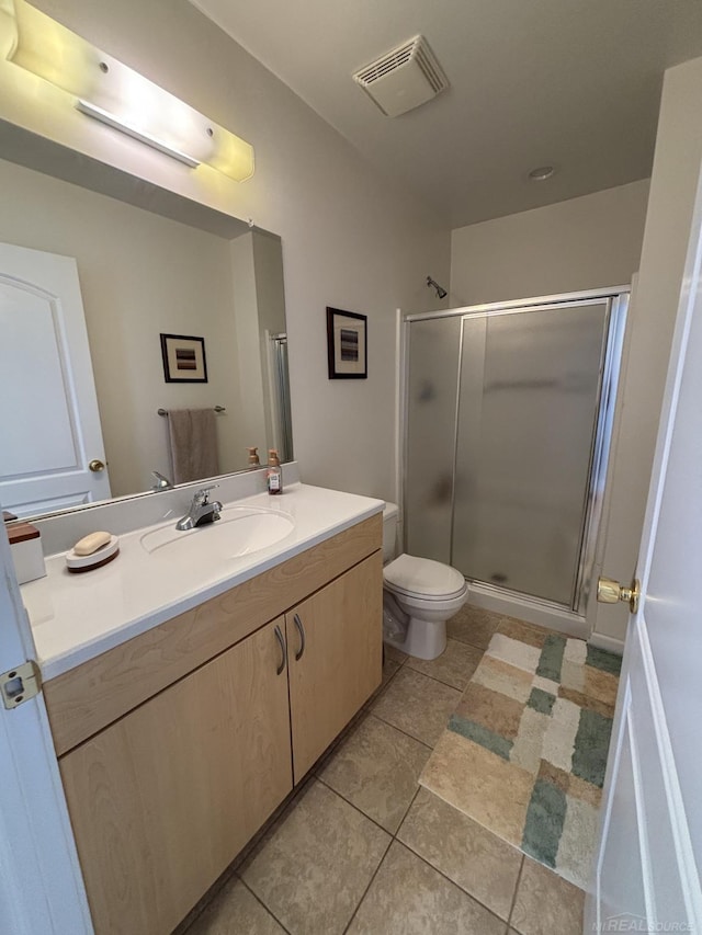 bathroom featuring tile patterned floors, vanity, toilet, and a shower with shower door