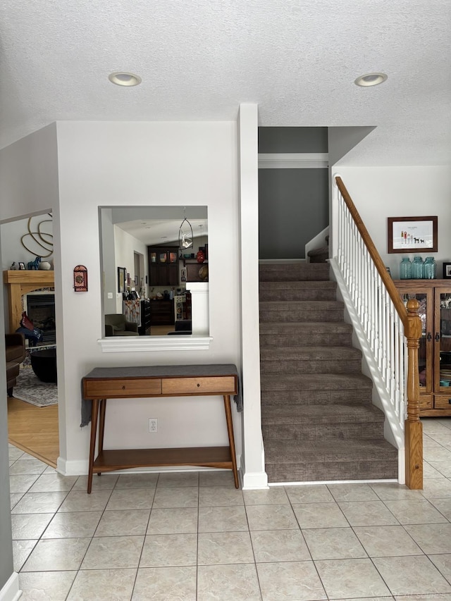 stairway featuring tile patterned floors and a textured ceiling