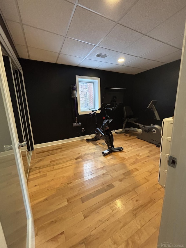 workout area featuring a paneled ceiling and light hardwood / wood-style floors