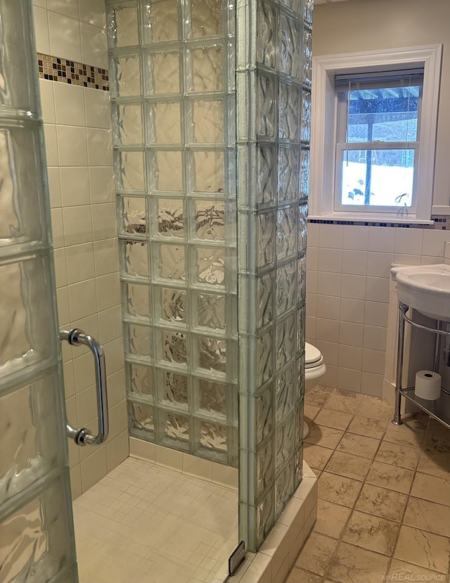 bathroom featuring toilet, a shower with door, tile walls, and tile patterned flooring