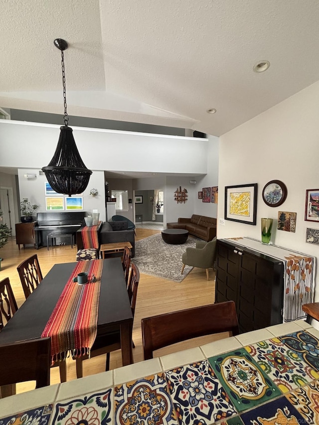 dining area featuring hardwood / wood-style floors, lofted ceiling, and a textured ceiling