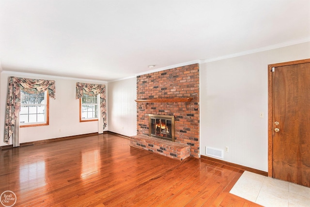 unfurnished living room with wood-type flooring, ornamental molding, and a brick fireplace