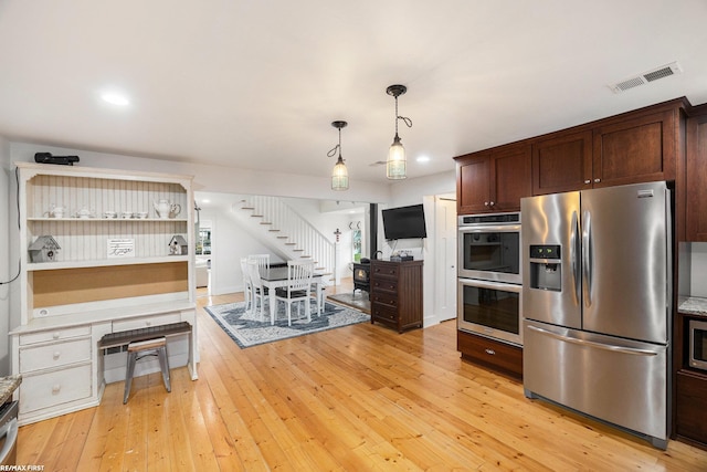 kitchen featuring light stone counters, dark brown cabinetry, stainless steel appliances, light hardwood / wood-style flooring, and hanging light fixtures