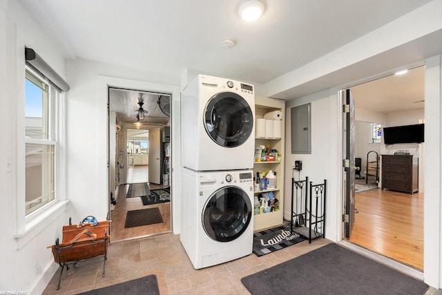 clothes washing area featuring electric panel and stacked washer / drying machine