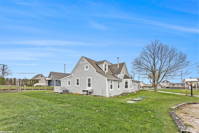 back of property with a lawn and central AC