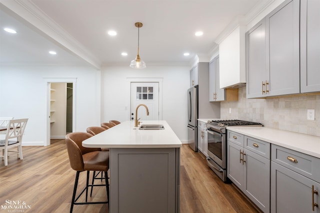 kitchen with crown molding, sink, gray cabinets, an island with sink, and stainless steel appliances